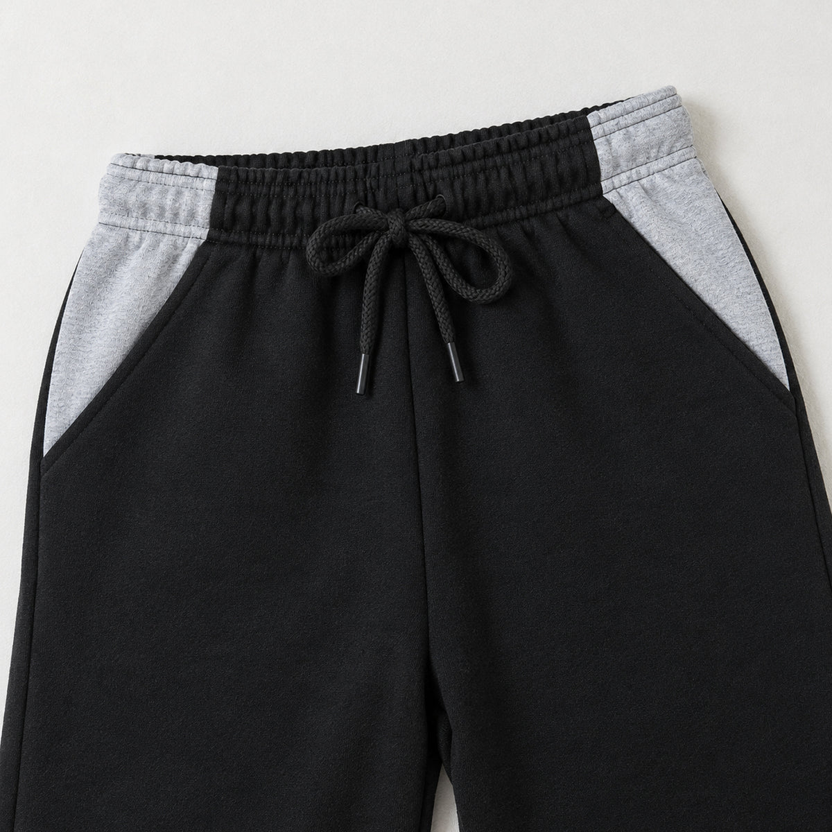 Kids black fleece trousers featuring two grey contrast side pockets and an elasticated drawstring waistband for boys and girls.
